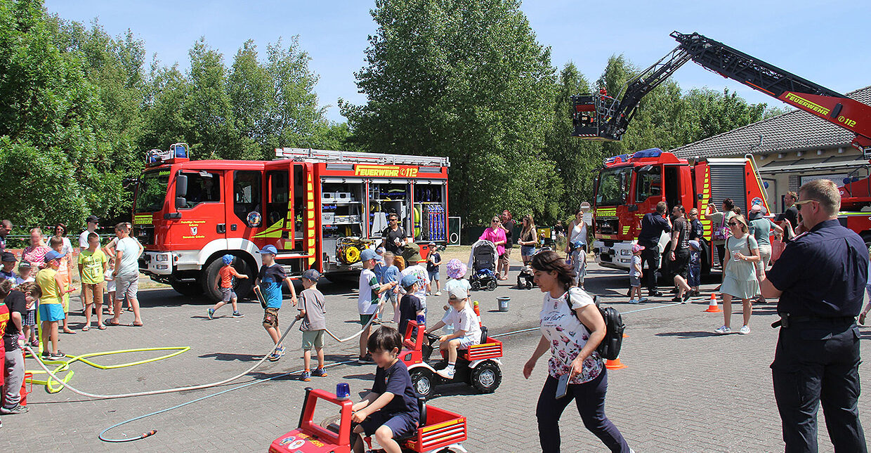 Reges Treiben auf dem Sommerfest der Ostseeklinik, ein Platz mit Kindern und Eltern in Bewegung, im Hintergrund ein Feuerwehrauto.