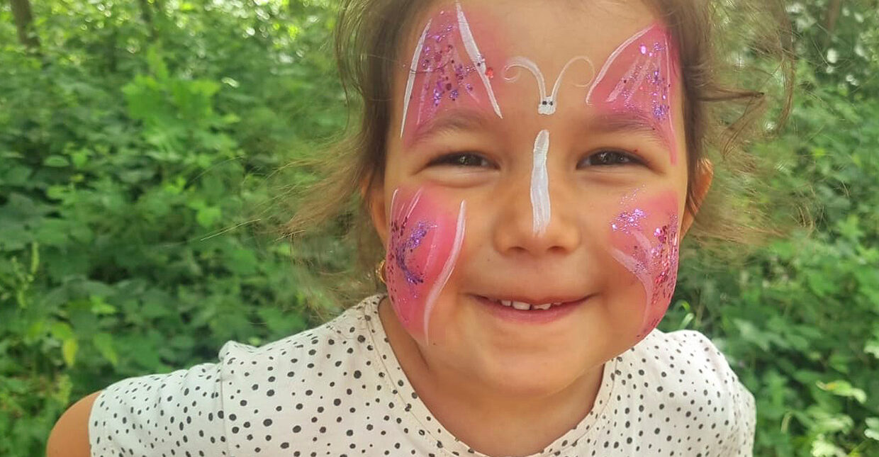 Ein Mädchen mit bemaltem Gesicht schaut lächelnd in die Kamera.