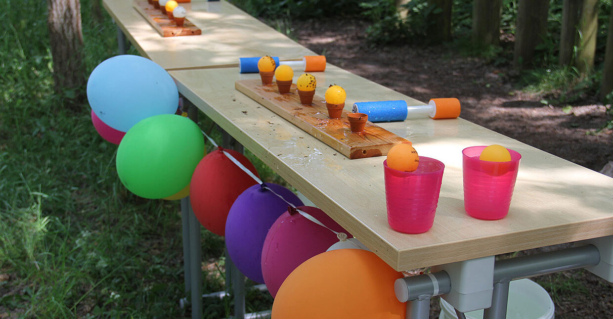Ein Tisch mit bunten Spielutensilien, der mit bunten Ballons geschmückt ist.